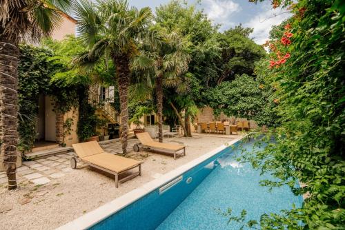 - une piscine avec 2 chaises longues et des palmiers dans l'établissement Villa Potoka Palace - 4 Bedroom Villa - Central and Private Setting - Spa and Sauna, à Jelsa