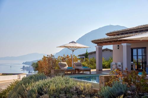 une maison avec deux chaises et un parasol dans l'établissement Angsana Corfu Resort & Spa, à Benitses