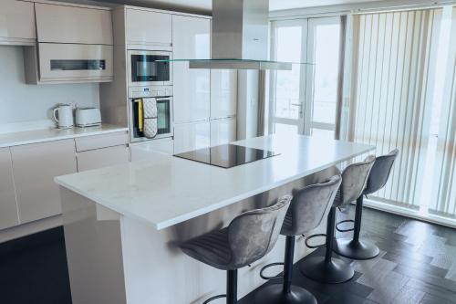 a kitchen with a white counter and stools at Luxury Three-Bedroom Penthouse- By Resify in Nottingham