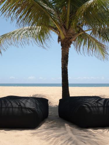 a palm tree and two bean bags on the beach at KA BRU 1100 Boutique Hotel in Taipu