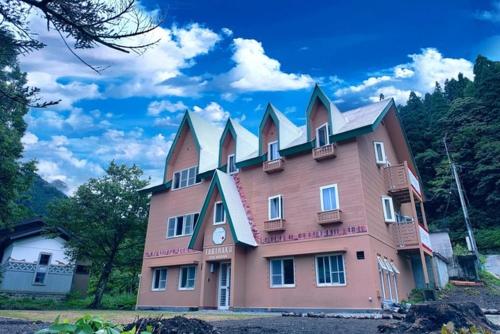 un grand bâtiment rose avec une horloge. dans l'établissement TABIHAKU STAY Hakusan - Vacation STAY 37435v, à Shirakawa-gō