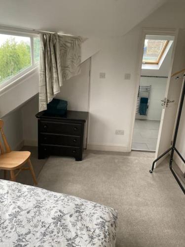 a bedroom with a bed and a dresser and a window at Cosy attic flat with views in London