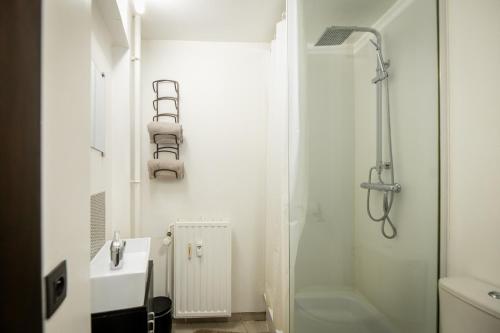 bagno bianco con doccia e lavandino di L'Endroit by la Reine city center a Spa
