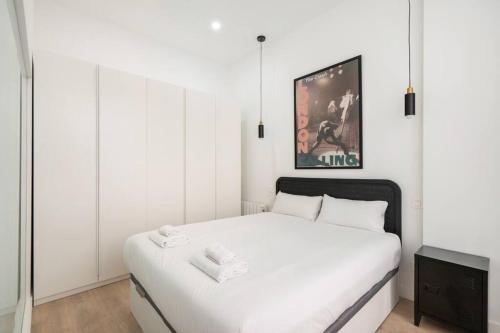 Biała sypialnia z białym łóżkiem i zdjęciem w obiekcie Bowie House - Madrid River-A-SALVAD w Madrycie