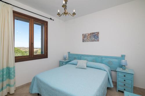 Un dormitorio con una cama azul y una ventana en Casa Vacanze La Pavoncella, en Trinità dʼAgultu