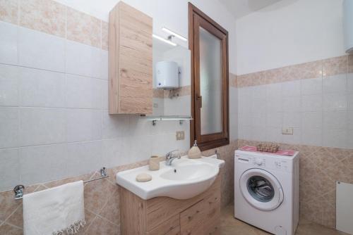 y baño con lavabo y lavadora. en Casa Vacanze La Pavoncella, en Trinità dʼAgultu