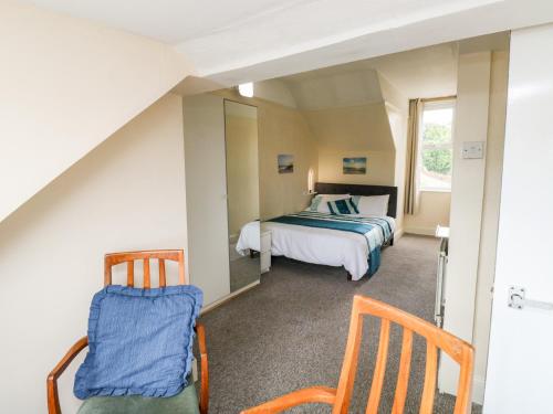 - une chambre avec un lit et deux chaises dans l'établissement Flat 2, à Teignmouth