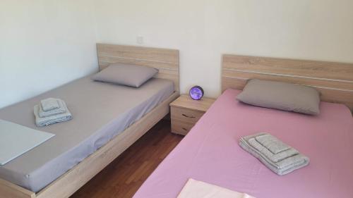 Duas camas individuais num quarto com lençóis cor-de-rosa em Seaty Apartment em Corinto