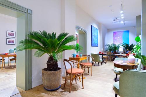 a restaurant with tables and chairs and a palm plant at ARCHE Dwór Uphagena Gdańsk in Gdańsk