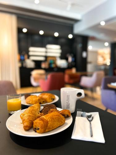 two plates of pastries on a table with orange juice at Martin's Louvain-la-Neuve in Louvain-la-Neuve