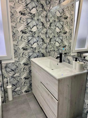 a bathroom with a sink and a black and white wallpaper at Soleado - En el centro de Gijón in Gijón