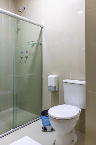 a bathroom with a toilet and a glass shower at Falcão Hotel Arapiraca in Arapiraca