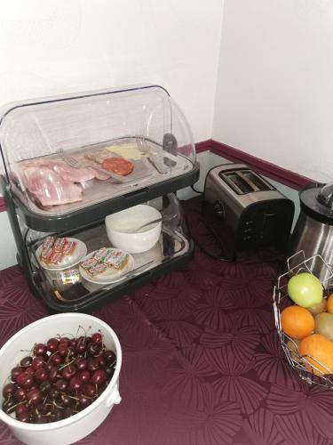 a table topped with bowls of fruit and a toaster at Hotel Restaurant La Grenouillère in Vitré