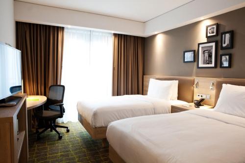 a hotel room with two beds and a desk at Hampton By Hilton Dortmund Phoenix See in Dortmund