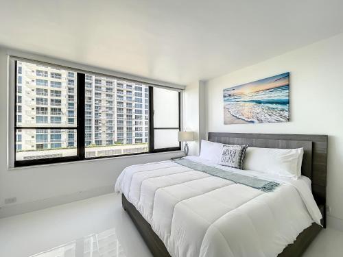 ハリウッドにあるBeach Paradise a cozy ocean view condo on the beach with free parkingの白いベッドルーム(大型ベッド1台、窓2つ付)