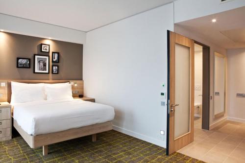 a bedroom with a white bed and a bathroom at Hampton By Hilton Dortmund Phoenix See in Dortmund