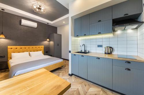 a bedroom with a bed and a kitchen with blue cabinets at Idea Design Apart-Hotel Prorizna in Kyiv