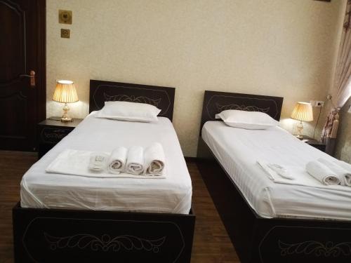 two beds in a hotel room with towels on them at Shafran B&B in Bukhara