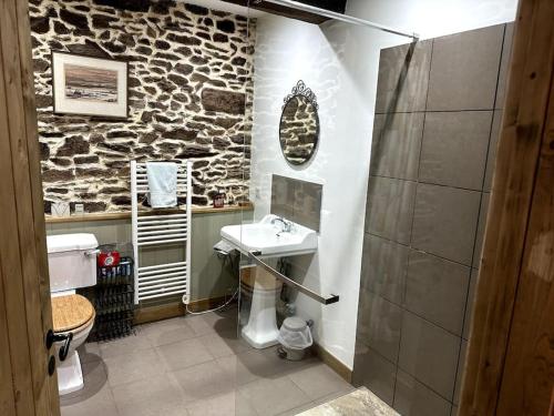 een badkamer met een wastafel en een stenen muur bij "L'Annexe" in Dournazac