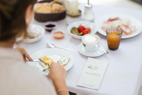 a woman sitting at a table with plates of food at Hotel Eichenhof in Tirolo