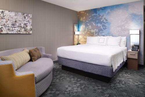 um quarto de hotel com uma cama e uma cadeira em Courtyard Cleveland Independence em Independence