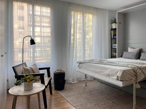 a bedroom with a bed and a chair and windows at Nice studio in neighbourhood Ibiza-NARV72 in Madrid