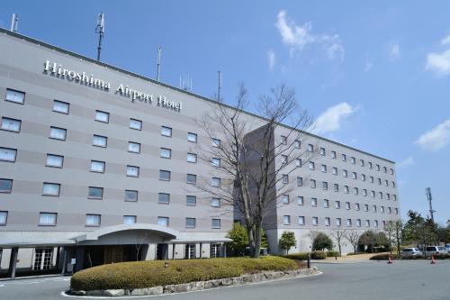 a large white building with a sign on it at Hiroshima Airport Hotel in Mihara