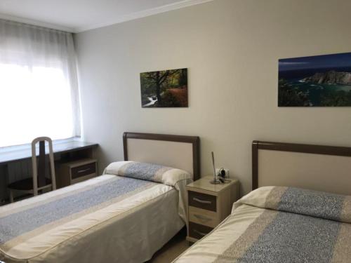 1 dormitorio con 2 camas y ventana en CasaBlanca, en Gijón