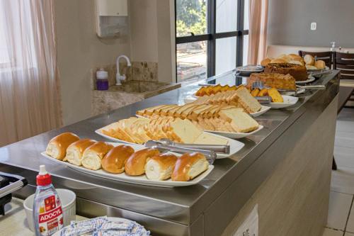 een buffet met borden met broodjes en andere voedingsmiddelen bij Falcão Hotel Arapiraca in Arapiraca