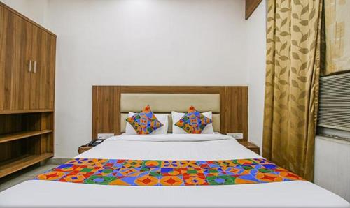 ein Schlafzimmer mit einem großen Bett mit einer bunten Bettdecke in der Unterkunft FabHotel Silver Inn I in Bhopal