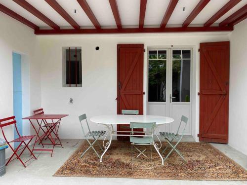 une table et des chaises dans une pièce avec portes rouges dans l'établissement Appartement en rez de jardin, à Ciboure