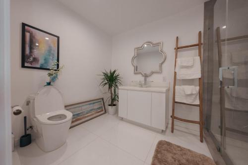 a white bathroom with a toilet and a mirror at Exclusive Hillside Hideaway-Private Room in Los Angeles