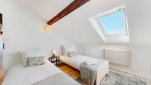 deux lits dans une chambre avec une fenêtre dans l'établissement Le Cocon Colmarien - Proche centre ville et gare - stationnement gratuit - 10 personnes, à Colmar