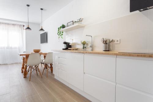 een keuken met witte kasten en een houten tafel bij Apartamento Piolín in L'Escala