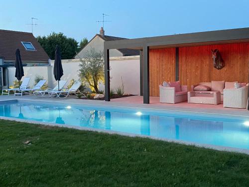 a backyard with a swimming pool with chairs and a house at Le Céladon in Larçay