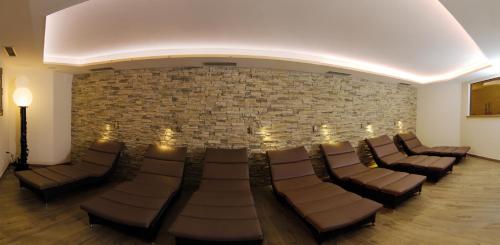 a waiting room with chairs and a brick wall at Hotel Eichenhof in Tirolo