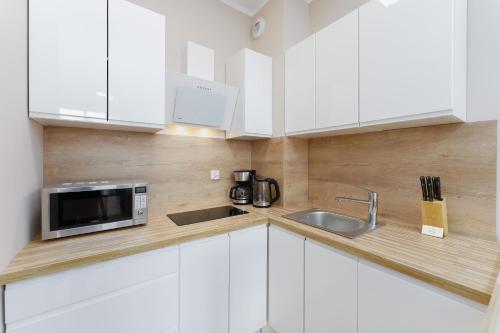 Apartament Słoneczny Ku Morzu by HolidaySun في سيانوزيتي: مطبخ بدولاب بيضاء ومغسلة وميكروويف