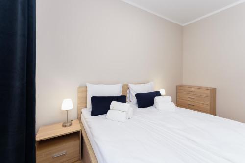 1 dormitorio con 1 cama blanca grande con almohadas azules en Apartament Słoneczny Ku Morzu by HolidaySun, en Sianożęty