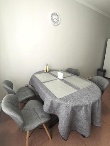 a dining room table with two chairs and a clock on the wall at Приватний будинок в Миколаєві з гаражем Private House in Mykolaiv with garage in Mykolaiv