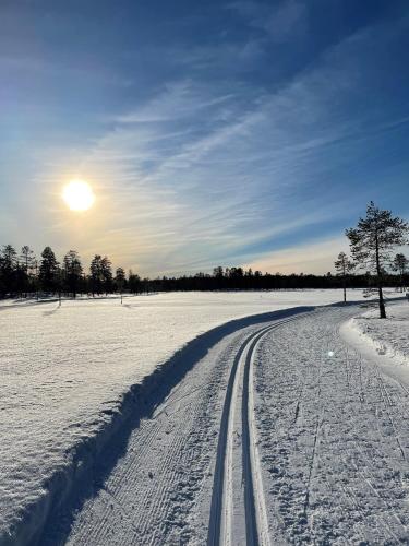 a road in a snowy field with the sun in the sky at Fryksås Hotell & Gestgifveri in Fryksås