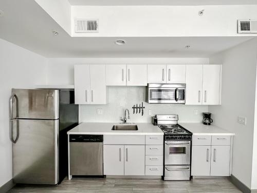 uma cozinha com armários brancos e um frigorífico de aço inoxidável em Sleepover High-end Downtown Springfield Apartments em Springfield