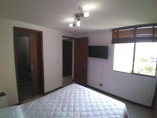 un dormitorio vacío con una cama y una ventana en Mayorca cómodo y central, en Sabaneta