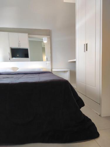 - une chambre avec un lit noir et une armoire blanche dans l'établissement Flat 704 Triângulo Apart, à Vitória