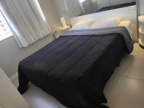 um quarto com uma cama grande e um cobertor preto em Flat 704 Triângulo Apart em Vitória