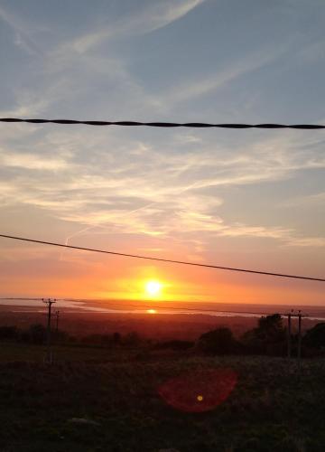 a sunset over a field with the sun in the sky at Kims Retreat in Caernarfon