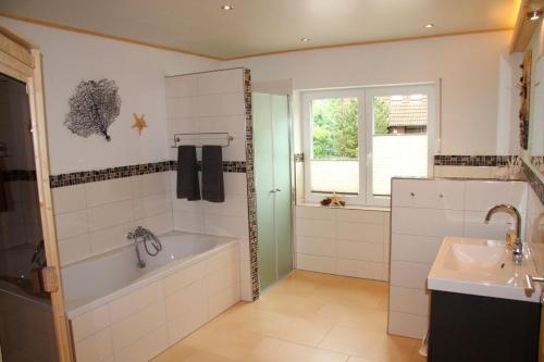a bathroom with a bath tub and a sink at Huus Strandgut 9140 - Fehmarn in Avendorf auf Fehmarn