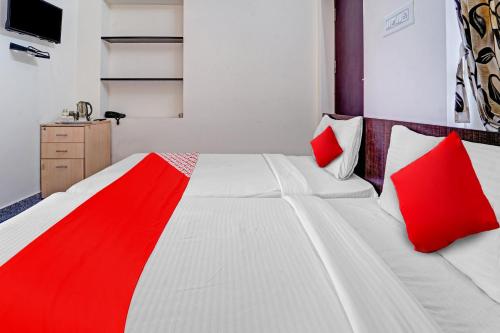 1 dormitorio con 2 camas blancas y almohadas rojas en Super OYO Flagship Royal Residency, en Nāmakkal