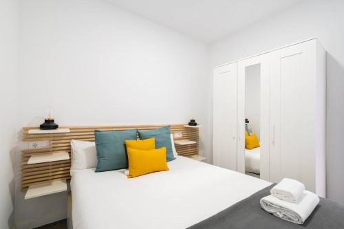 een slaapkamer met een wit bed met gele en blauwe kussens bij Nice apartment in the center of Madrid-S-EL-VERDE in Madrid