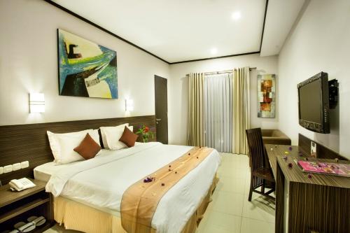 a bedroom with a bed and a desk and a television at Summer Hills Hotel & Villas Bandung in Bandung