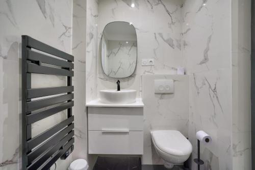uma casa de banho branca com um WC e um espelho. em Magnifique appartement proche Tour Eiffel em Paris